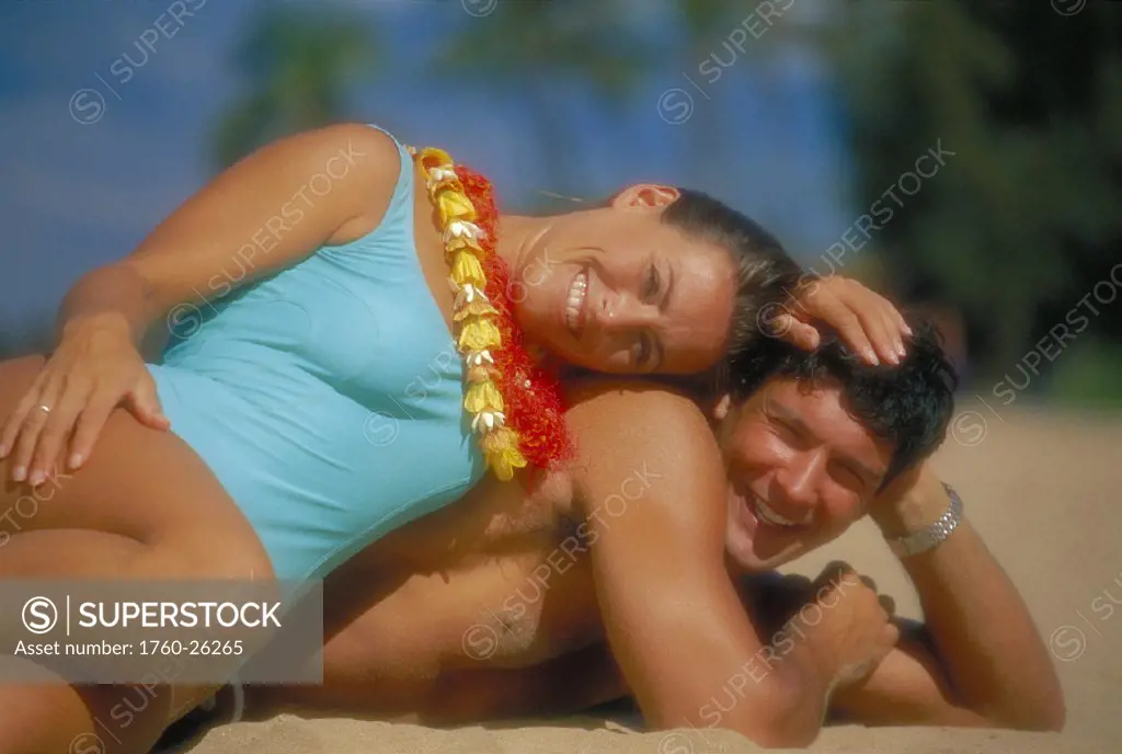 Hawaii Maui Makena couple lay on beach woman atop man smile together, lei D1060