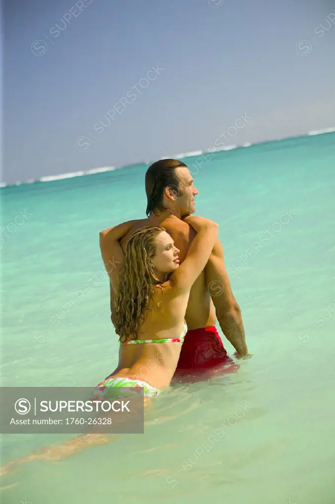 Hawaii, Oahu, Lanikai, Woman leaning on man´s back in turquoise ocean.