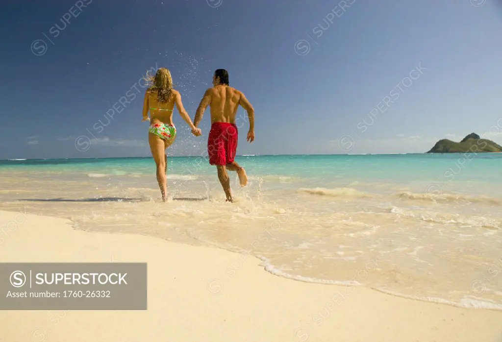 Hawaii, Oahu, Lanikai, Couple run on the beach holding hands.