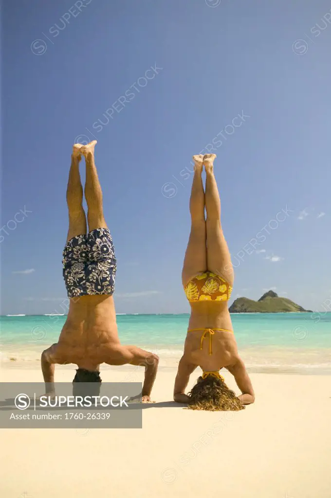 Hawaii, Oahu, Lanikai, Man and woman stand on there heads on the beach.