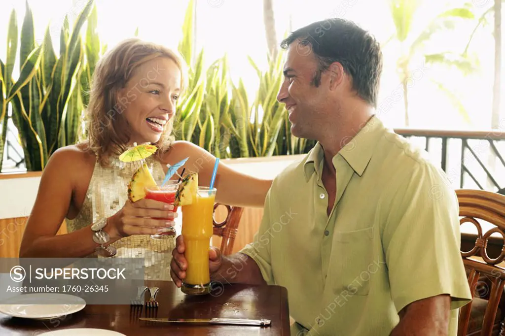 Tourist couple at an island style bar enjoying cocktails