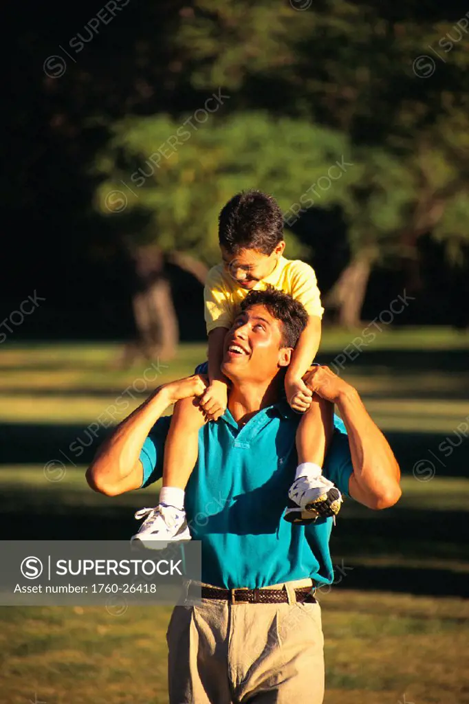 Father with son on shoulders walk through park B1092