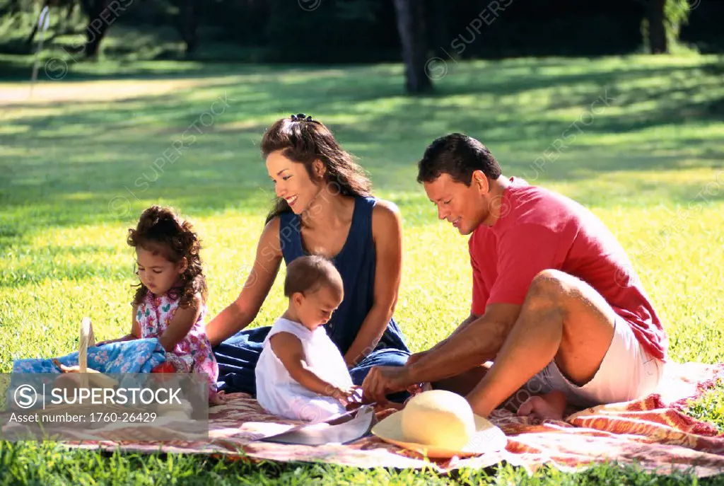 Local family at park, picnic on blanket, children with toys