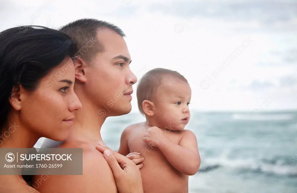 Hawaii, Oahu, Profile portrait of young attractive family of three looking out at the ocean.