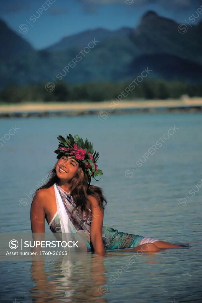 Hawaii, Polynesian beauty with flower lei in water at beach, smiling