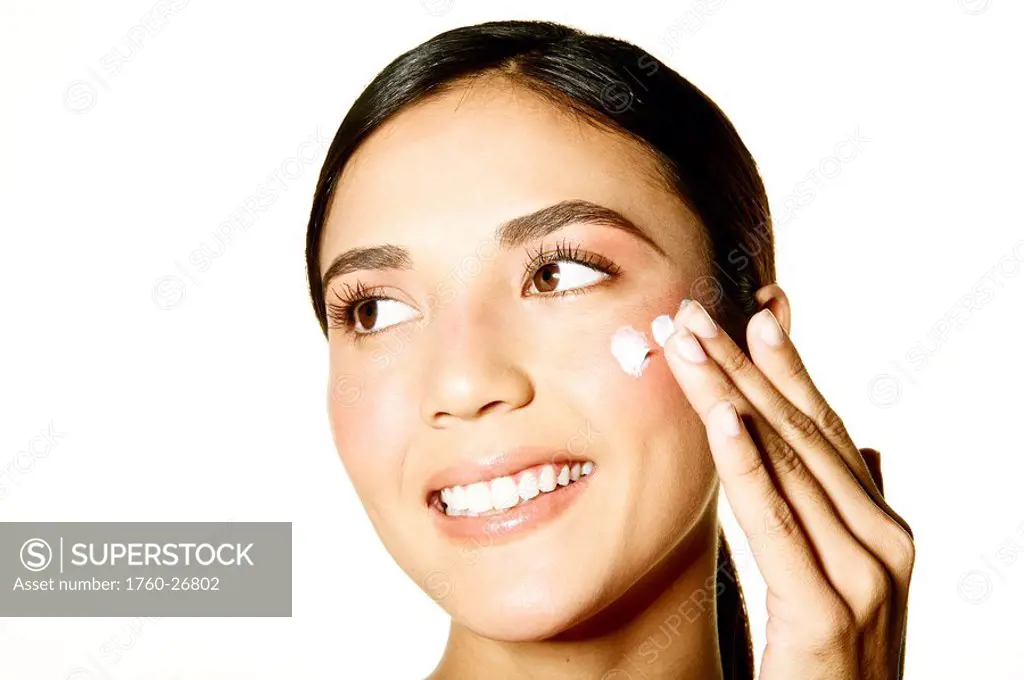 Hawaii, Studio headshot of a beautiful girl applying moisturizer on her skin.