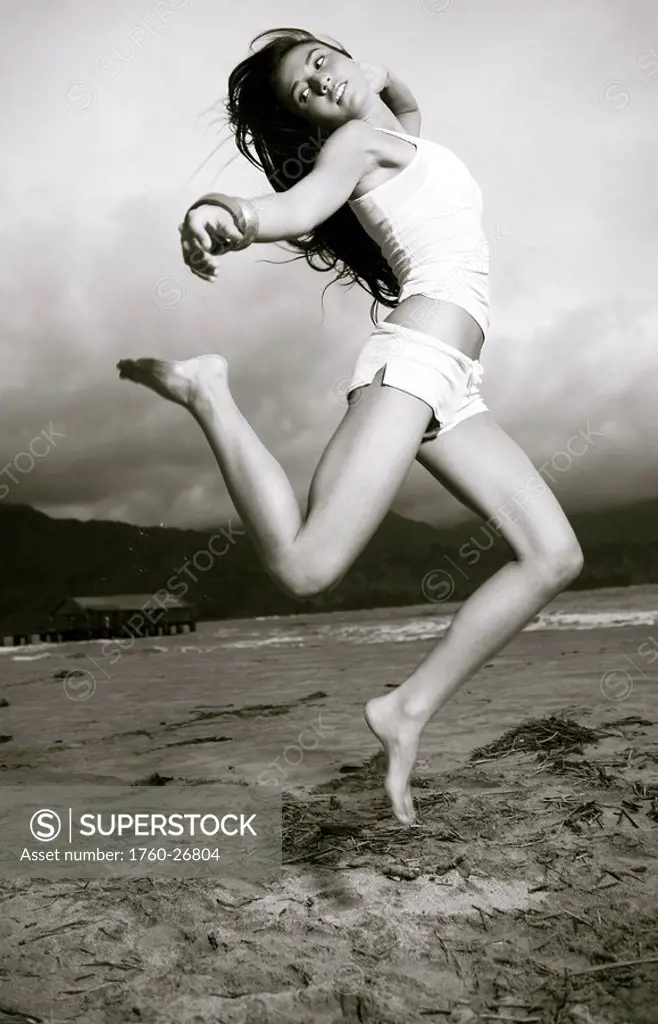 Hawaii, Kauai, Kealia beach, Attractive young woman on the beach jumping.