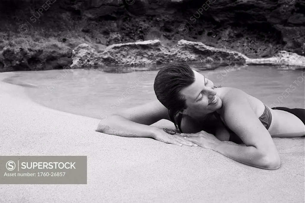 Hawaii, Kauai, Kauapea Beach Secret Beach Beautiful woman resting on the sand, black and white.