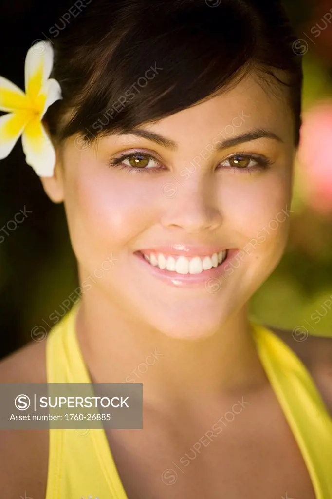 Hawaii, Oahu, Beautiful headshot of a young girl with a plumeria in her ear.
