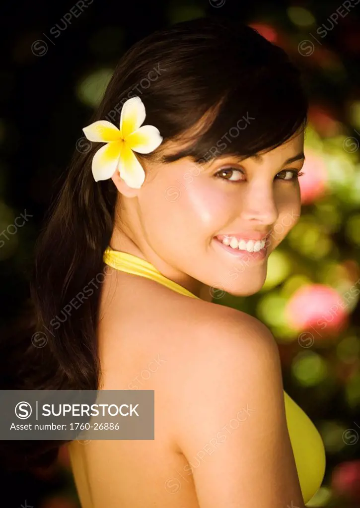 Hawaii, Oahu, Beautiful headshot of a young girl with a plumeria in her ear.
