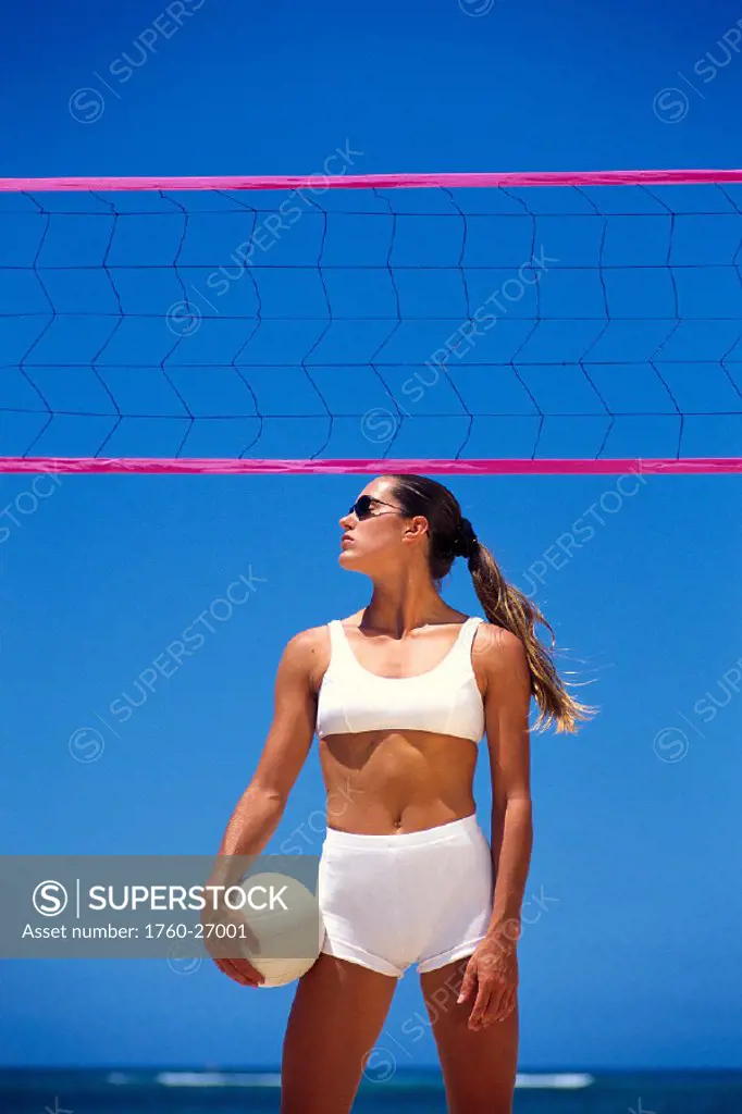 Beach volleyball woman on beach w/ ball at net, blue sky B1191