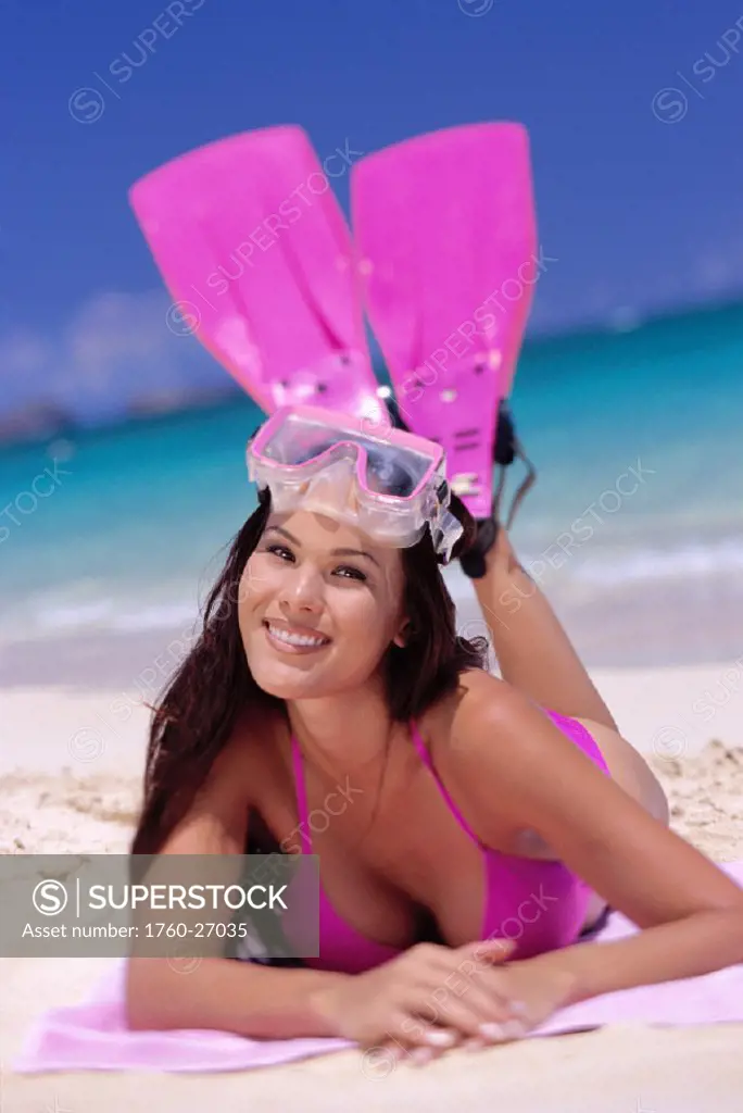 Closeup of smiling woman on beach, pink fins and mask, white sand, blue sky