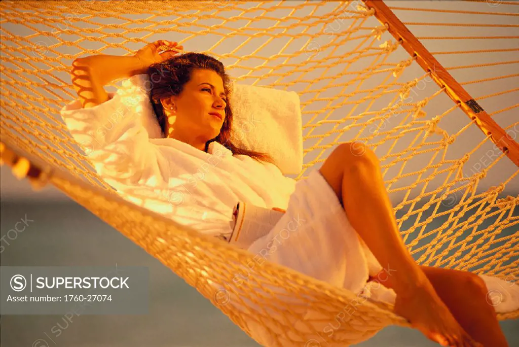 Woman relaxes in beach chair on beach, clear shore waters fades to turquoise C1100
