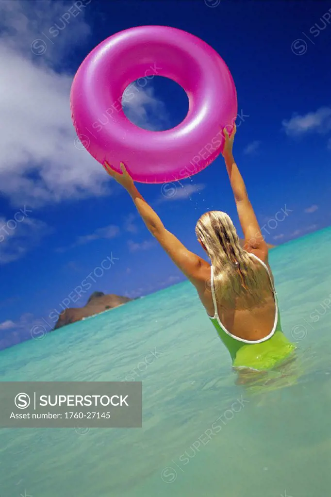 Lanikai Beach, back view of woman in bathingsuit holding pink innertube D1083 over her head