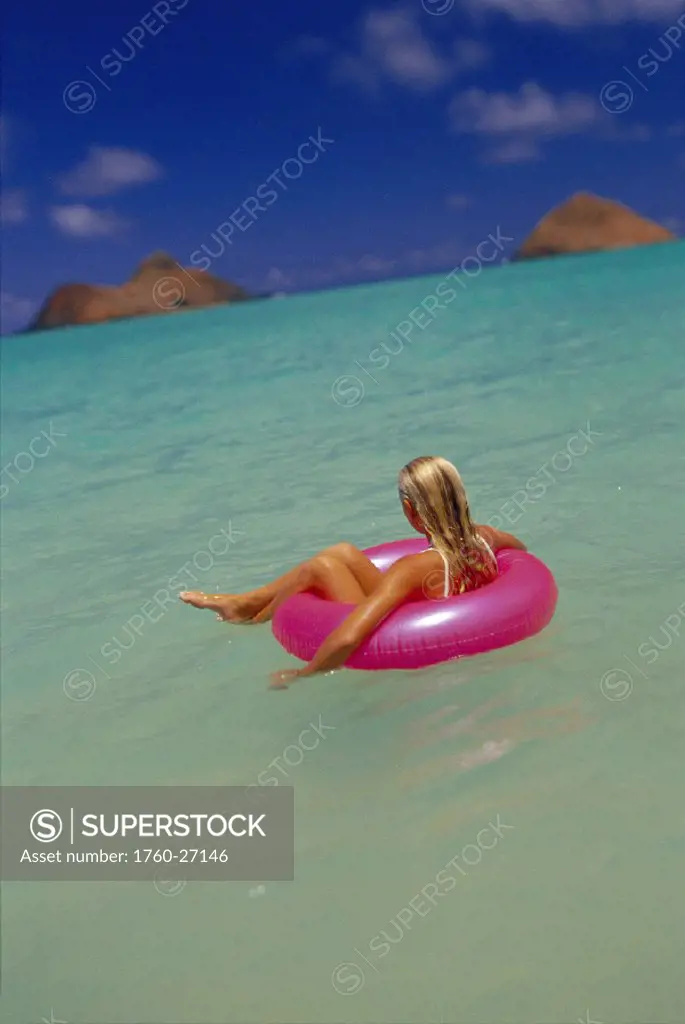 HI Lanikai Beach young woman sits in pink innertube, turquoise ocean D1105