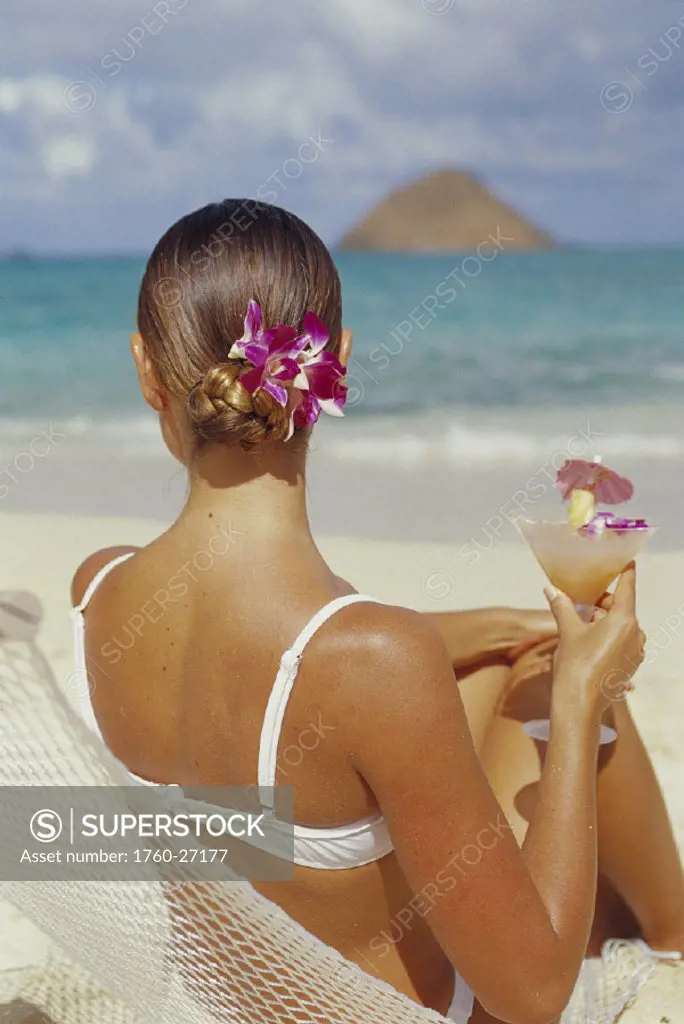 Back vu of woman in hammock, holding tropical drink, beach, Mokulua Is.