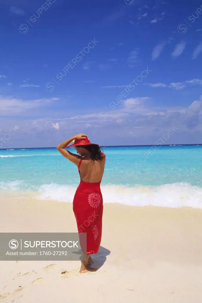 Mexico, Cancun, woman in red on white sand beach, view from behind.