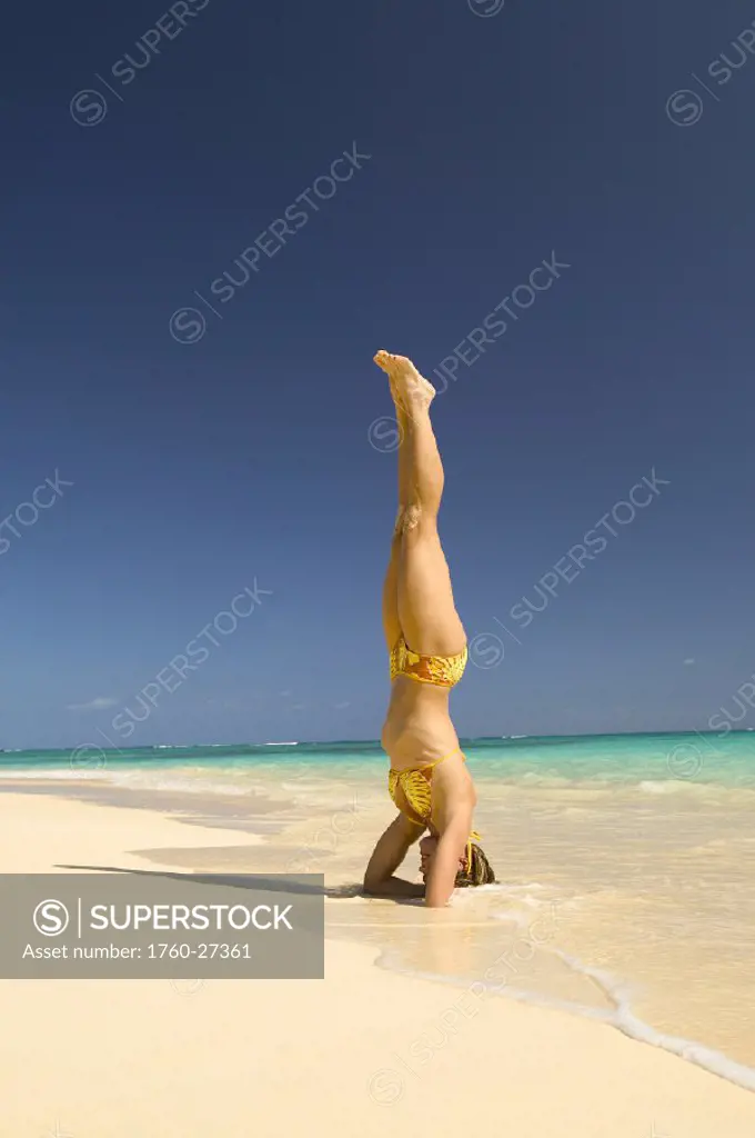 Hawaii, Oahu, Lanikai,  and woman stands on her head on the beach.