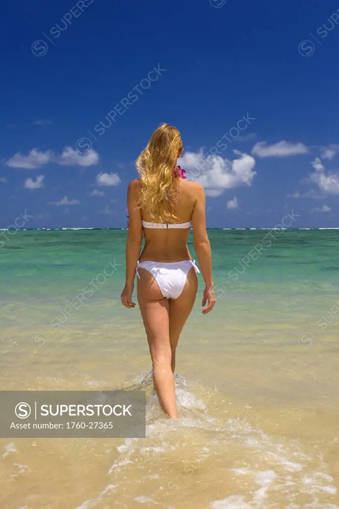 Hawaii, Oahu, Punaluu Beach, Beautiful young woman walking into turquoise ocean.