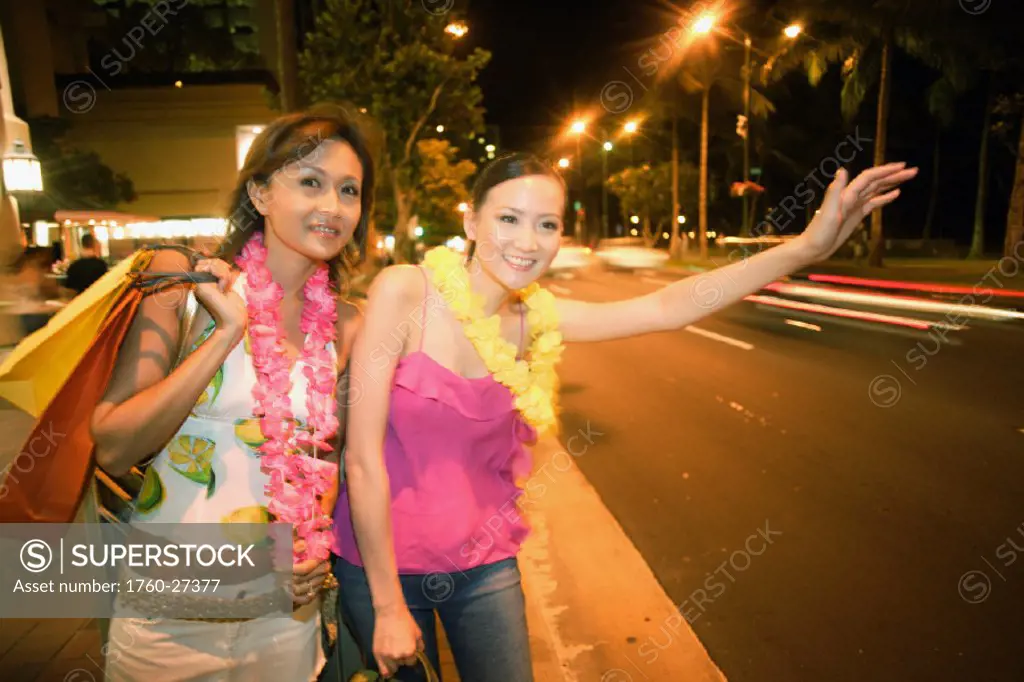Hawaii, Oahu, Honolulu, Two female Japanese tourists hail a taxi in Waikiki.