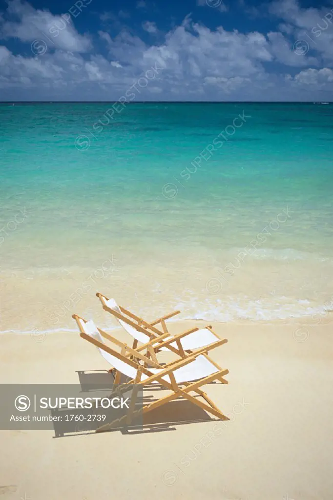 Pair of beach chairs along calm shoreline waters, white sand C1711
