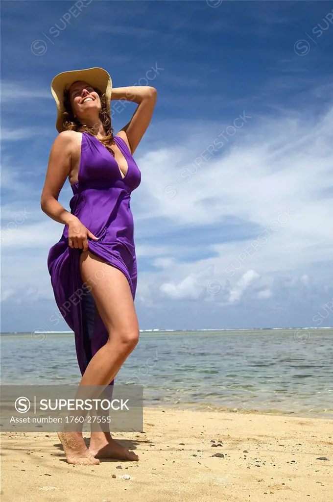 Hawaii, Kauai, Anini Bay, Woman walking the beach with a purple dress on.