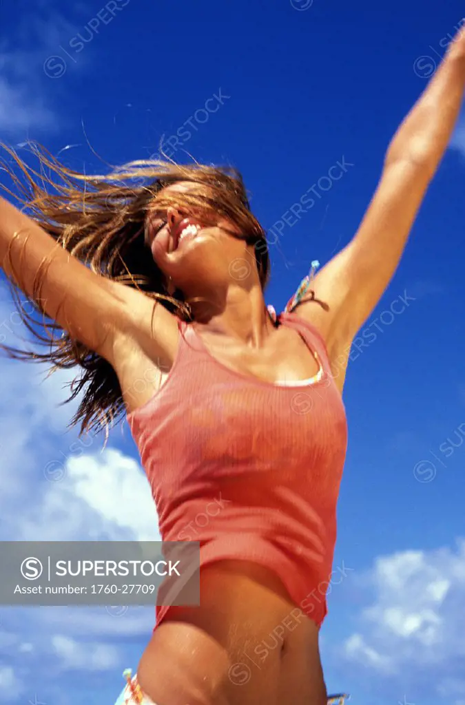 Teen girl with arms spread up against clear blue sky, joy/freedom.
