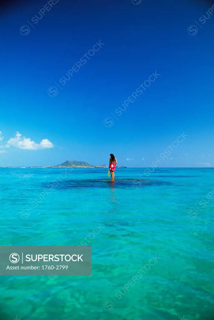 Hawaii, Oahu, Lanikai, Distant. Woman standing on reef, lei, pareo.