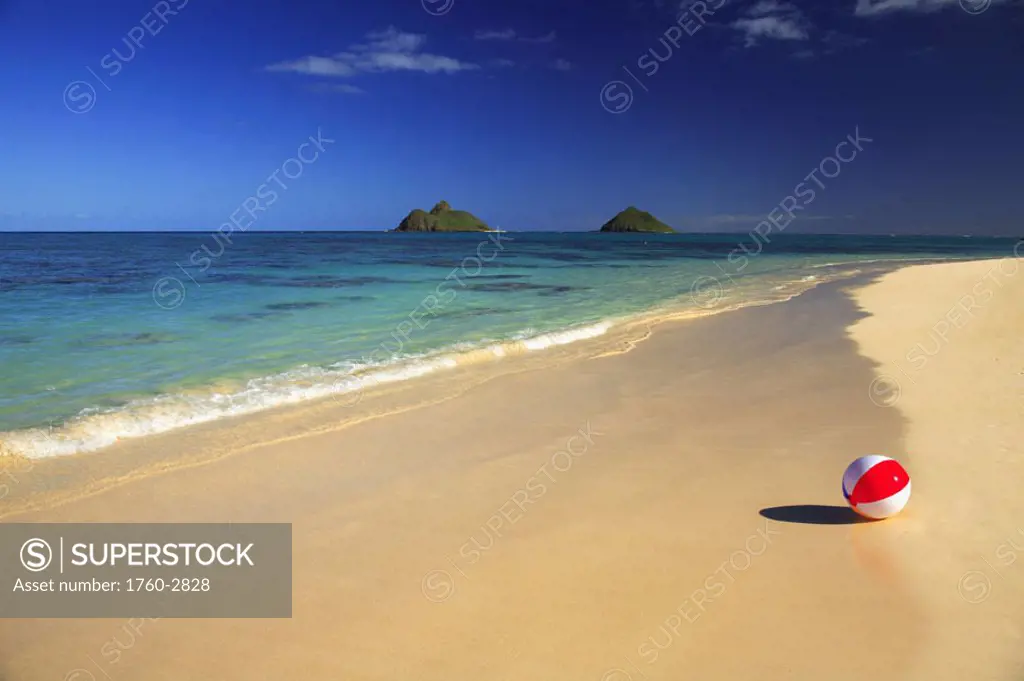 Hawaii, Oahu, Lanikai, Colorful beachball on the shore of tropical beach, Mokulua islands in background.