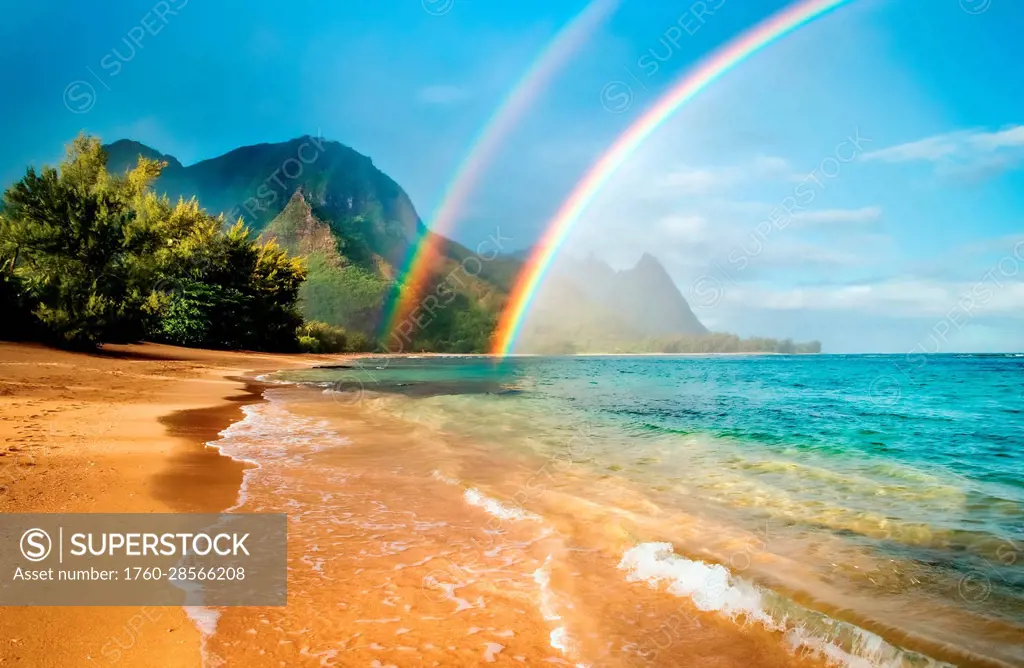 A double rainbow over the coastline of a Hawaiian island with mountains and turquoise water; Haena, Kauai, Hawaii, United States of America
