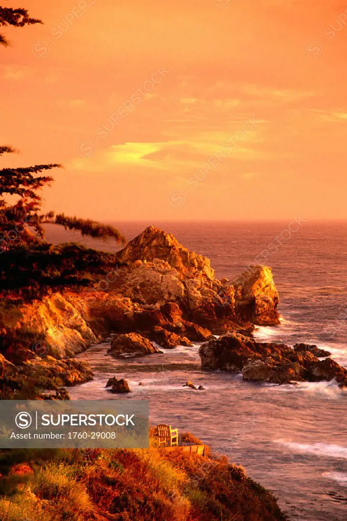California, Big Sur, Coastline view at sunset, yellow orange sky, chair