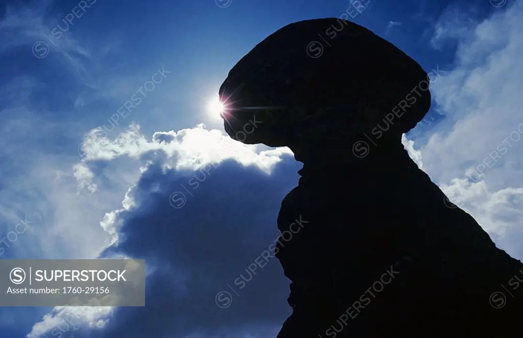 Utah, Arches National Park, Balanced Rock silhouetted against sunlight, Clouds in blue sky