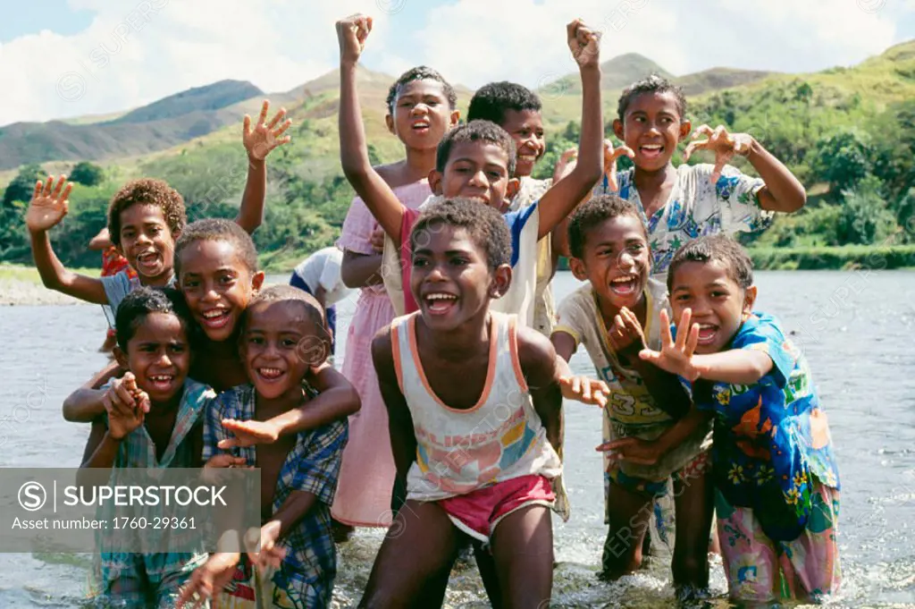 Fiji, group of children in river smiling for camera