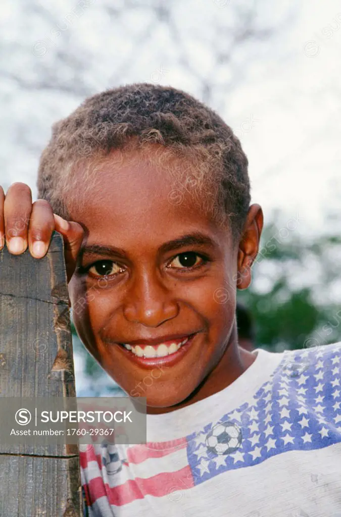 Fiji, headshot of smiling Fijian boy, outdoors