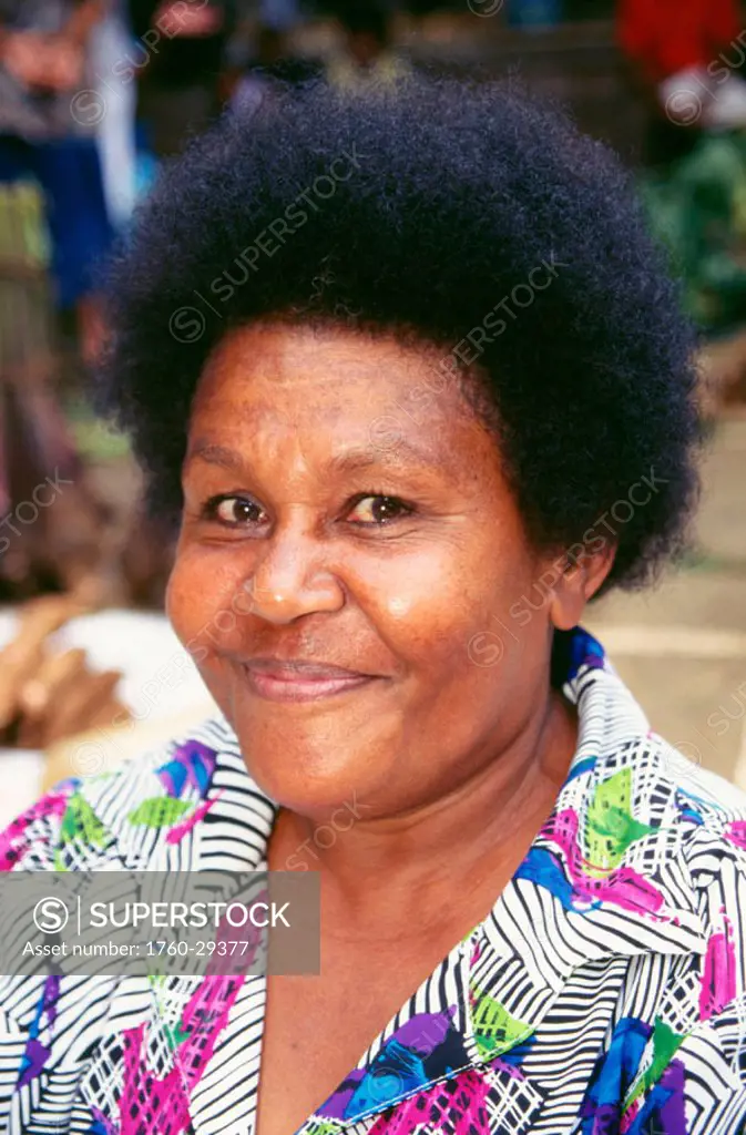 Fiji, Headshot of smiling Fijian woman outdoors, wearing colorful printed blouse