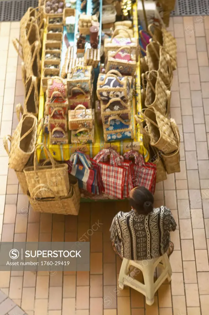 French Polynesia, Tahiti, Papeete, Vendor sitting in marketplace selling purses and bags, view from above. NO MODEL RELEASE