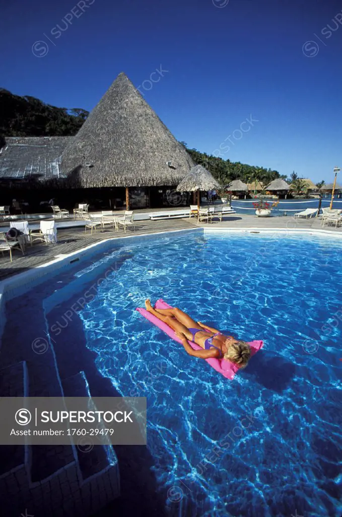 French Polynesia, Bora Bora, Hotel Moana Resort, Woman lying on inflatable raft in pool.