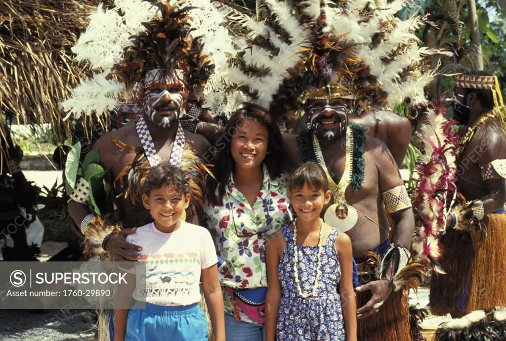 Solomons, native men wearing traditional face paint and costume pose with tourist family NO MODEL RELEASE