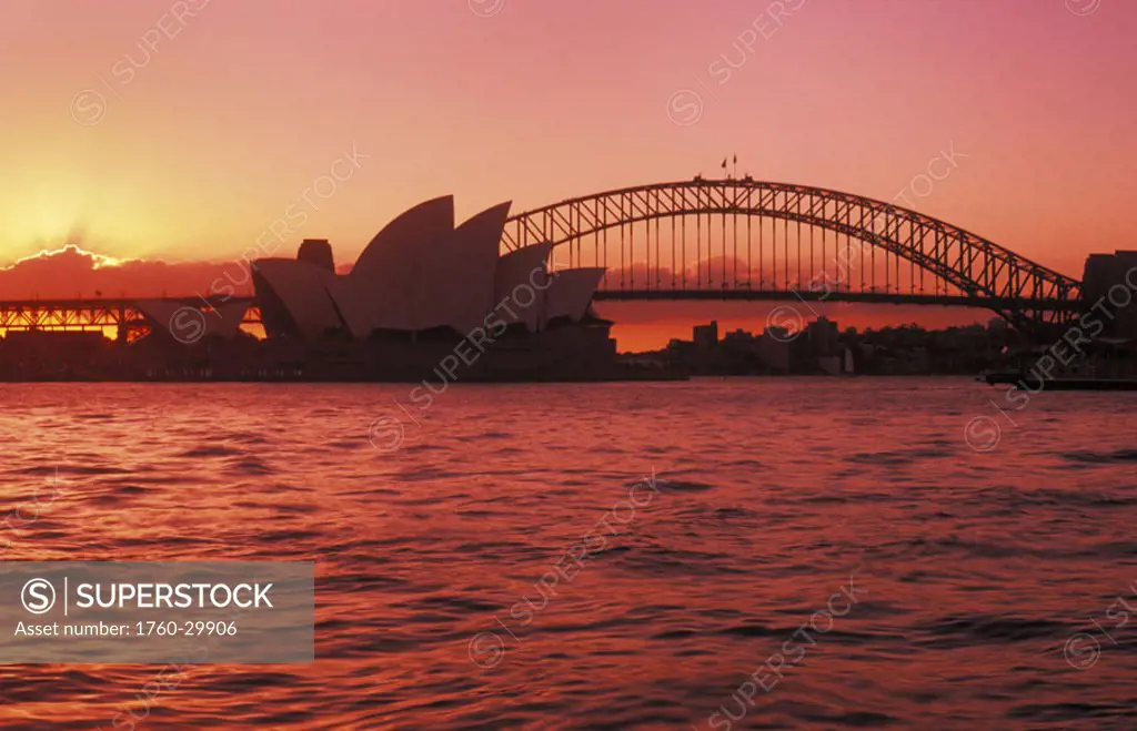 Australia, New South Wales, Sydney, Opera House and Harbour Bridge, bright red and pink sunset.