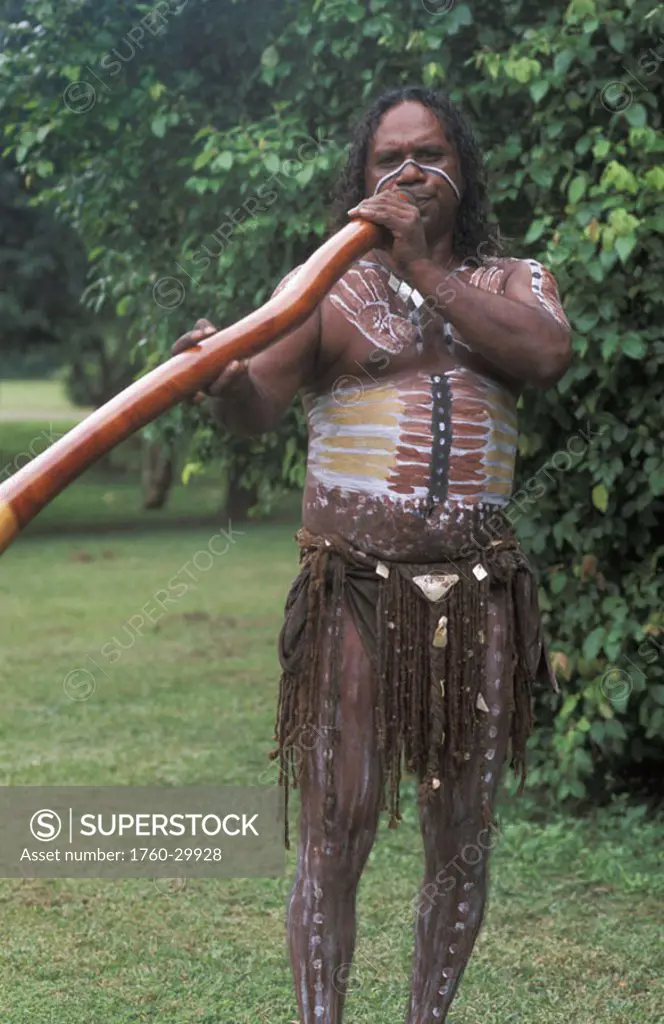 Australia, Queensland, Cairns,  Aboriginal native man playing didgeridoo, paint on body.