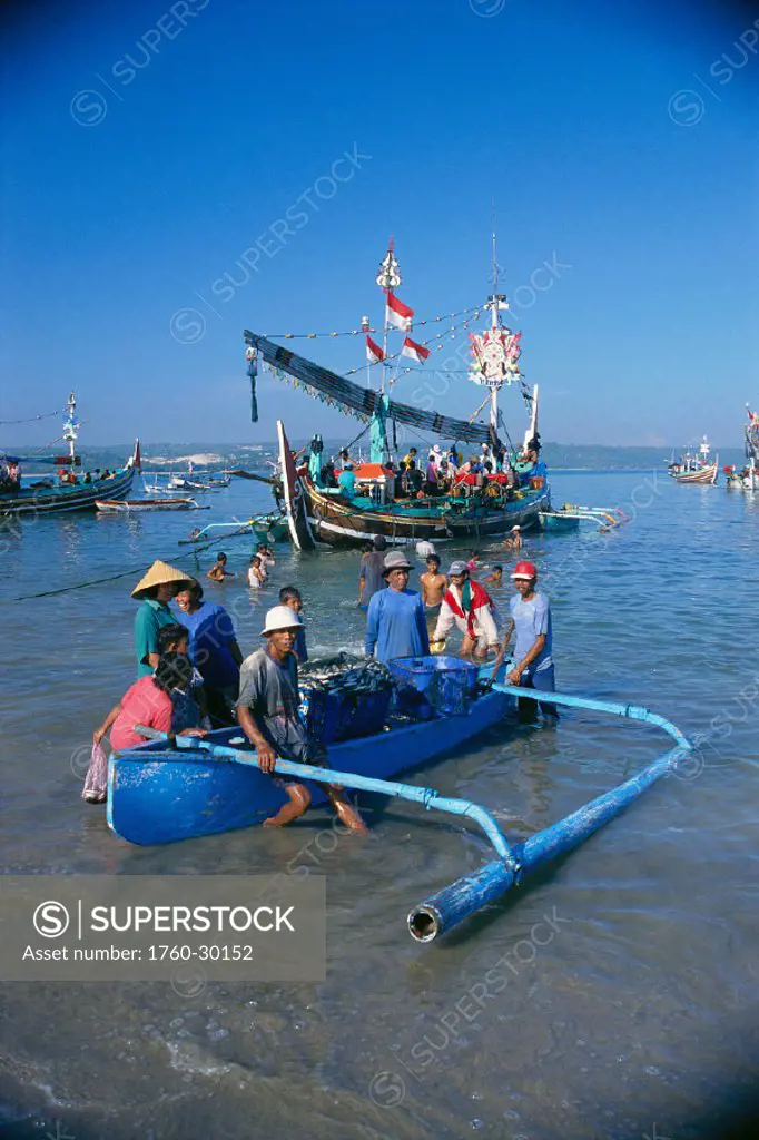 Indonesia, Bali, Jimbaran Bay, outrigger canoe w/ many local people, fishing fleet