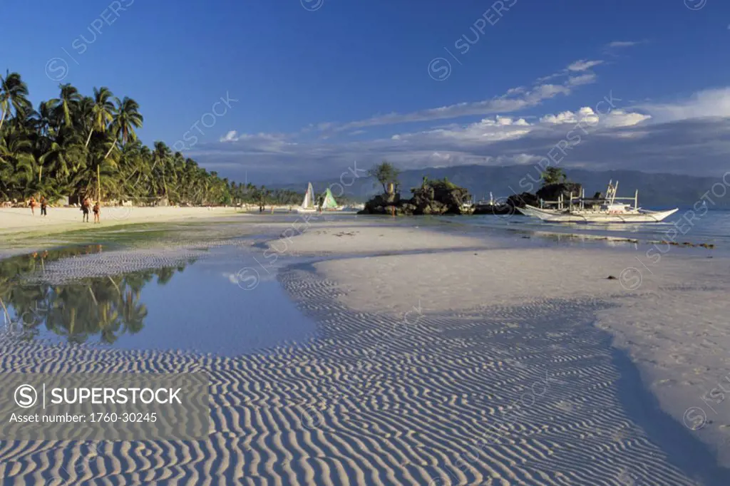 Philippines, Boracay Island, sand texture along shoreline boats anchored, people walk on white sand beach