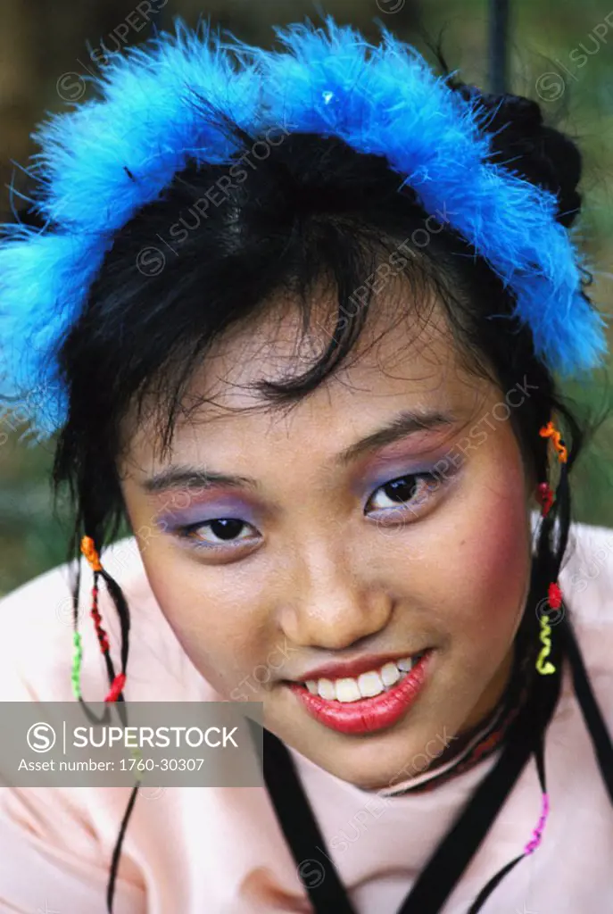 Singapore, headshot of smiling young woman with feather headpiece NO MODEL RELEASE