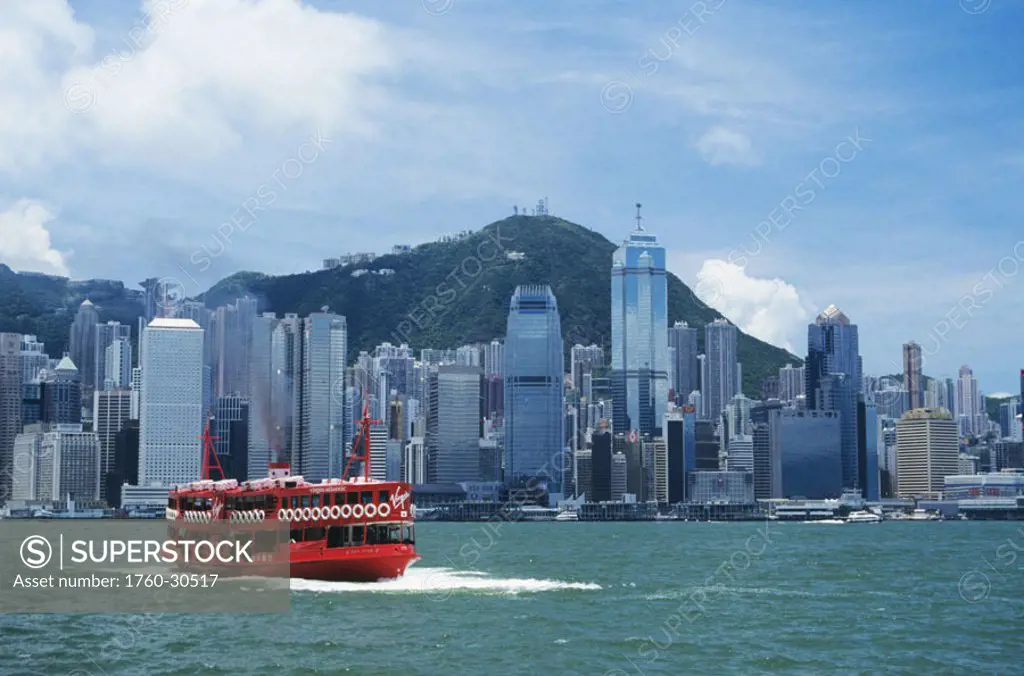Hong Kong, Hong Kong Harbor, view of business district with large red Virgin Atlantic ferry in foreground.