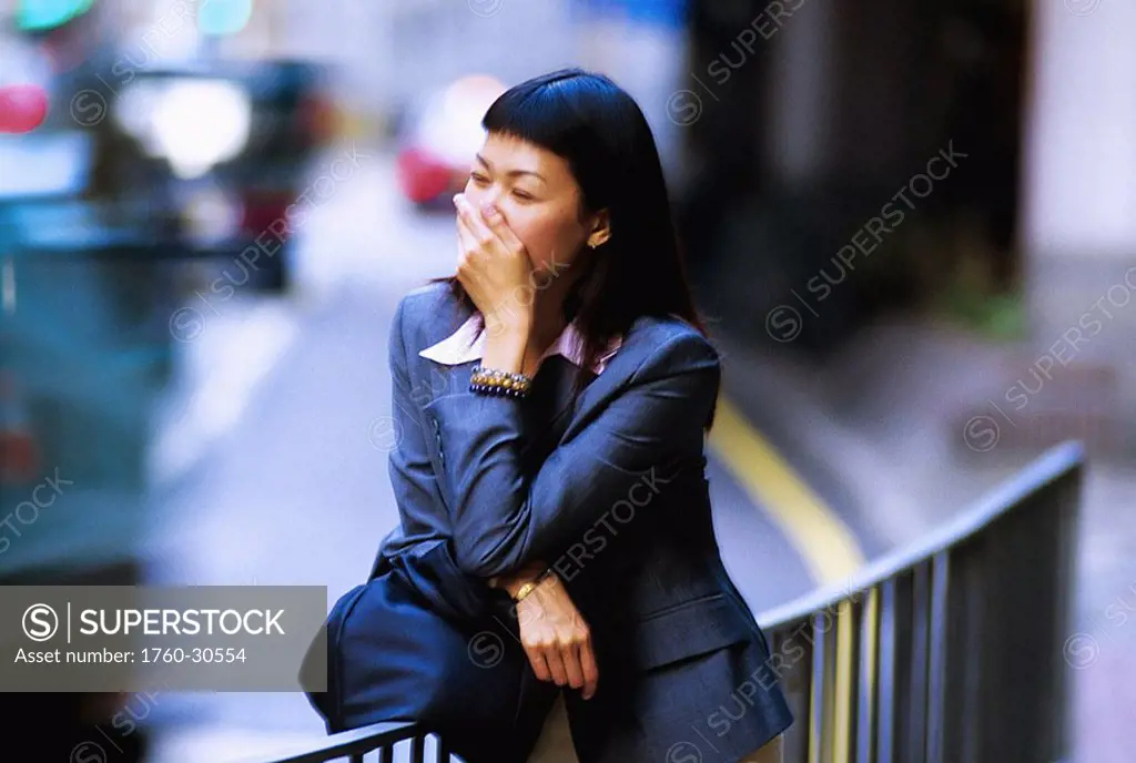 Hong Kong, Young Chinese business woman laughing on roadside