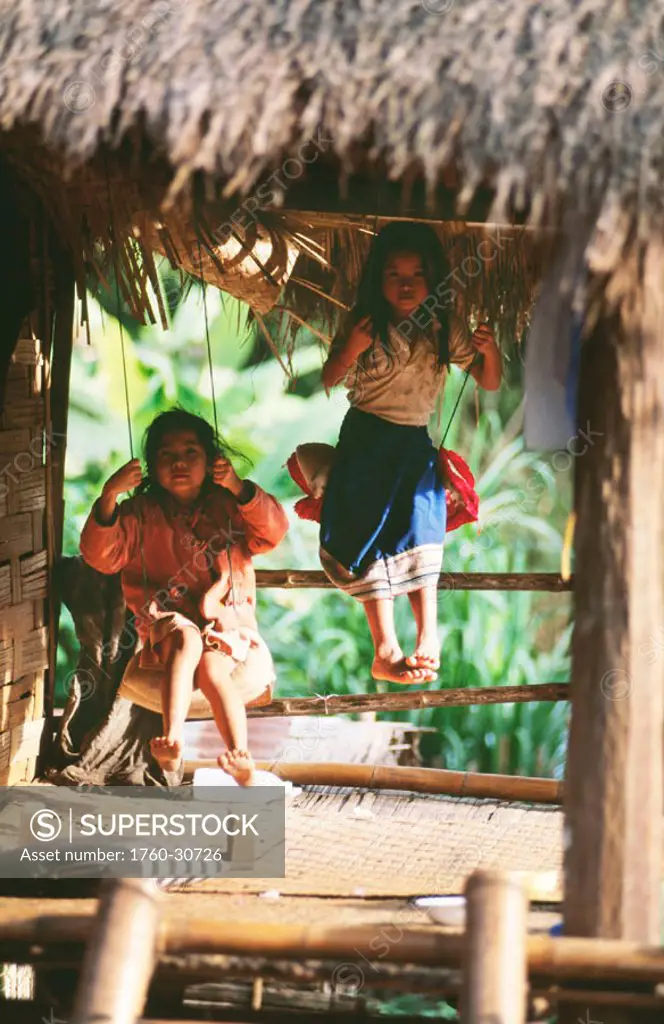 Laos, Luang Prabang, Two little girls on swings at their house.