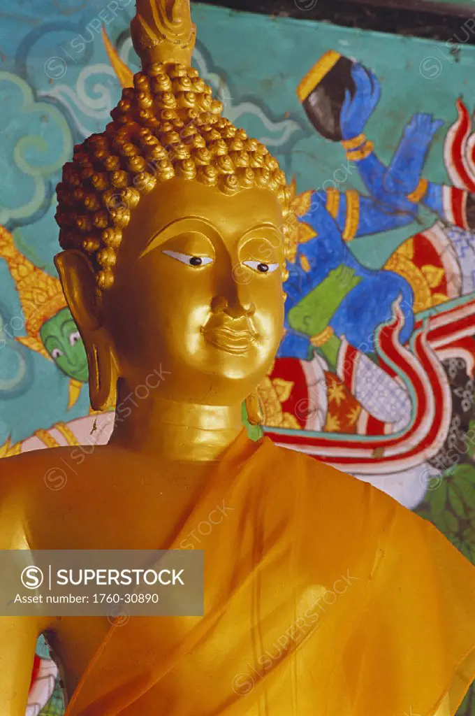 Thailand Lop Buri closeup of Buddha statue w/ saffron robe colorful painted background