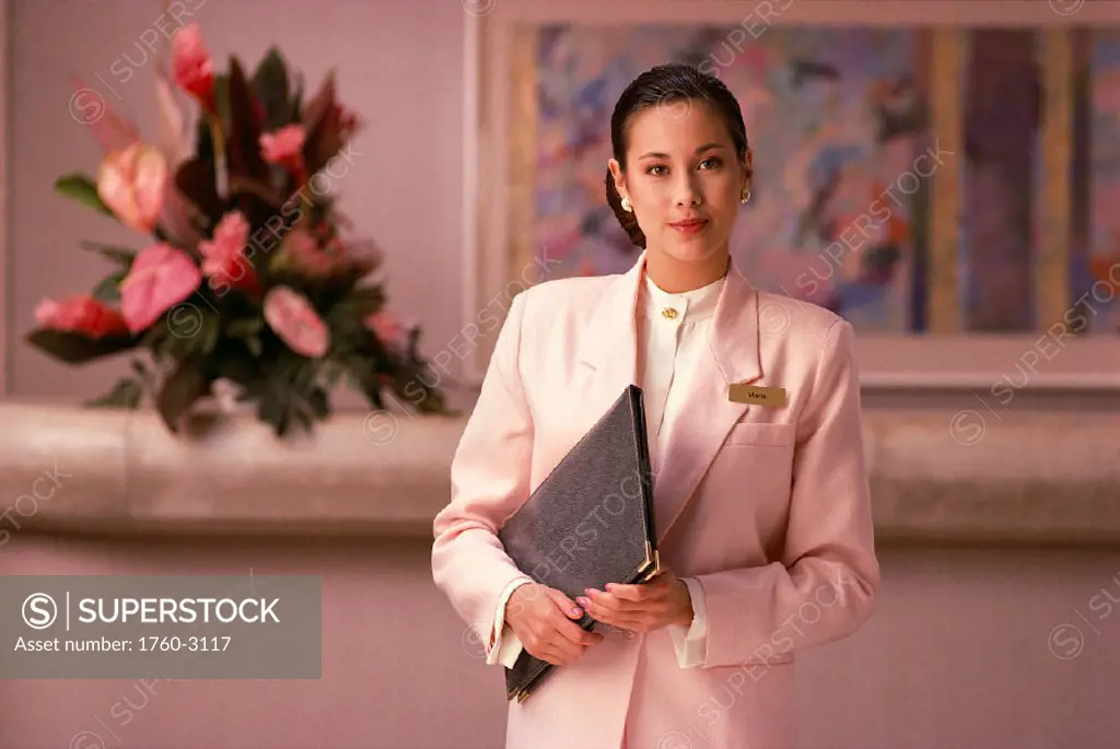 Young woman hotel concierge, soft pastel suit compliments surroundings B1135