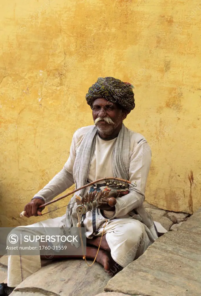 India, Senior local man sits cross-legged on stairs playing music instrument ´NO MODEL RELEASE´
