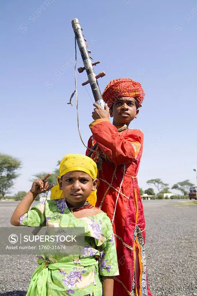 India, Rajasthan, road to Jodhpur, Young boy with musical instrument called Sarangi and young dancing sister
